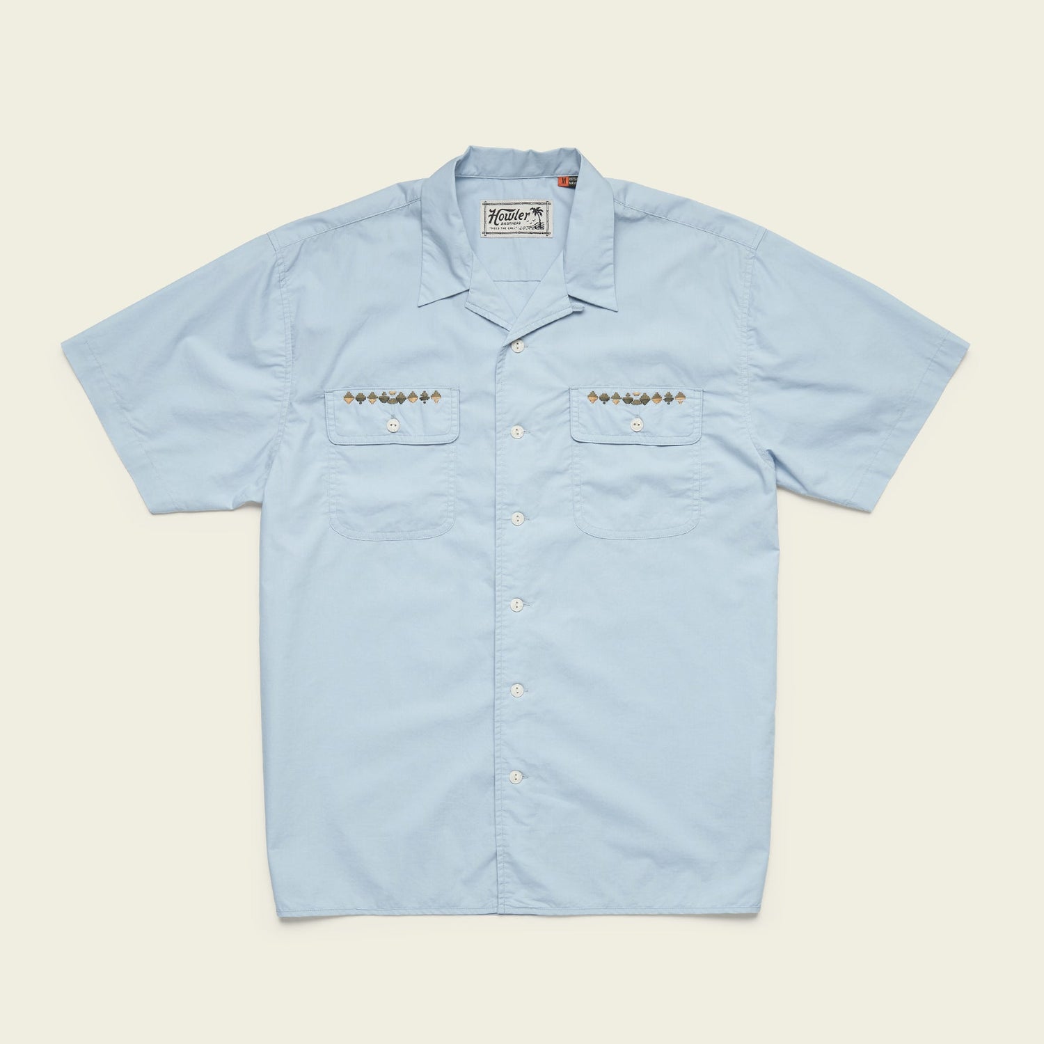 Light blue Shores Club Shirt with short sleeves and two chest pockets featuring geometric embroidery and small brown buttons. This camp collar shirt also has white front buttons, a classic collar, and decorative stitching on the pockets. - View 4