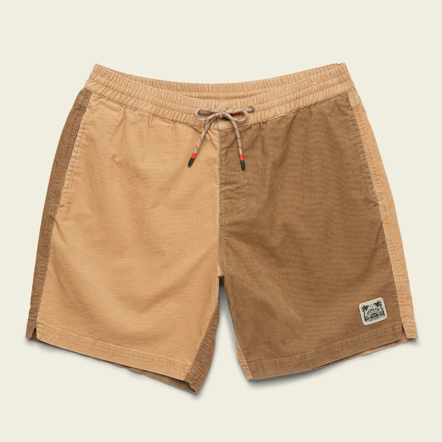 A pair of two-tone Pressure Drop Cord Shorts crafted from stretch cotton corduroy, featuring an elastic waistband, drawstring, and a small palm tree patch. The left side is light tan while the right side is a darker brown shade. - View 11