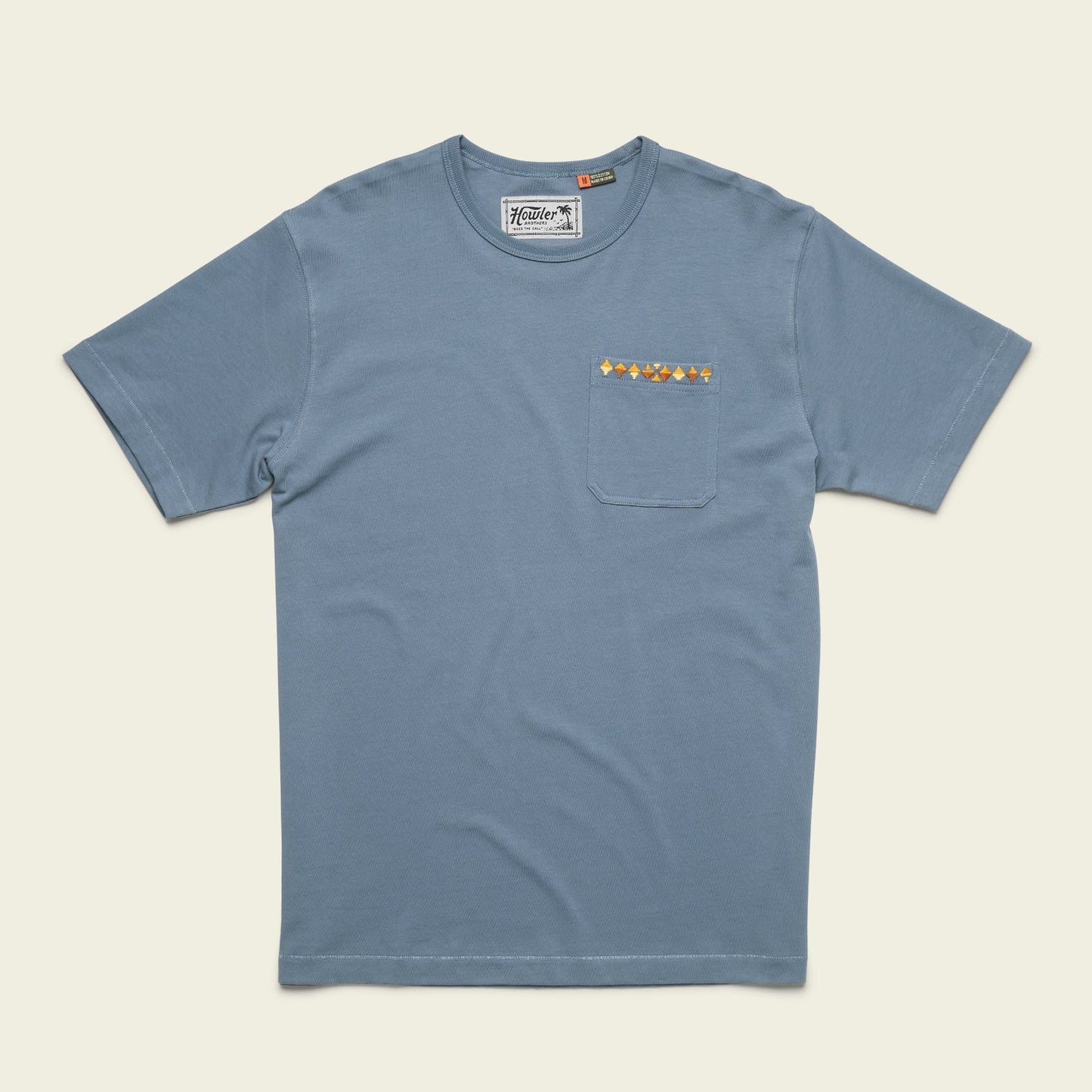 A blue, vintage inspired t-shirt made from heavyweight cotton, featuring a chest pocket adorned with a horizontal row of small, colorful geometric shapes. - View 8
