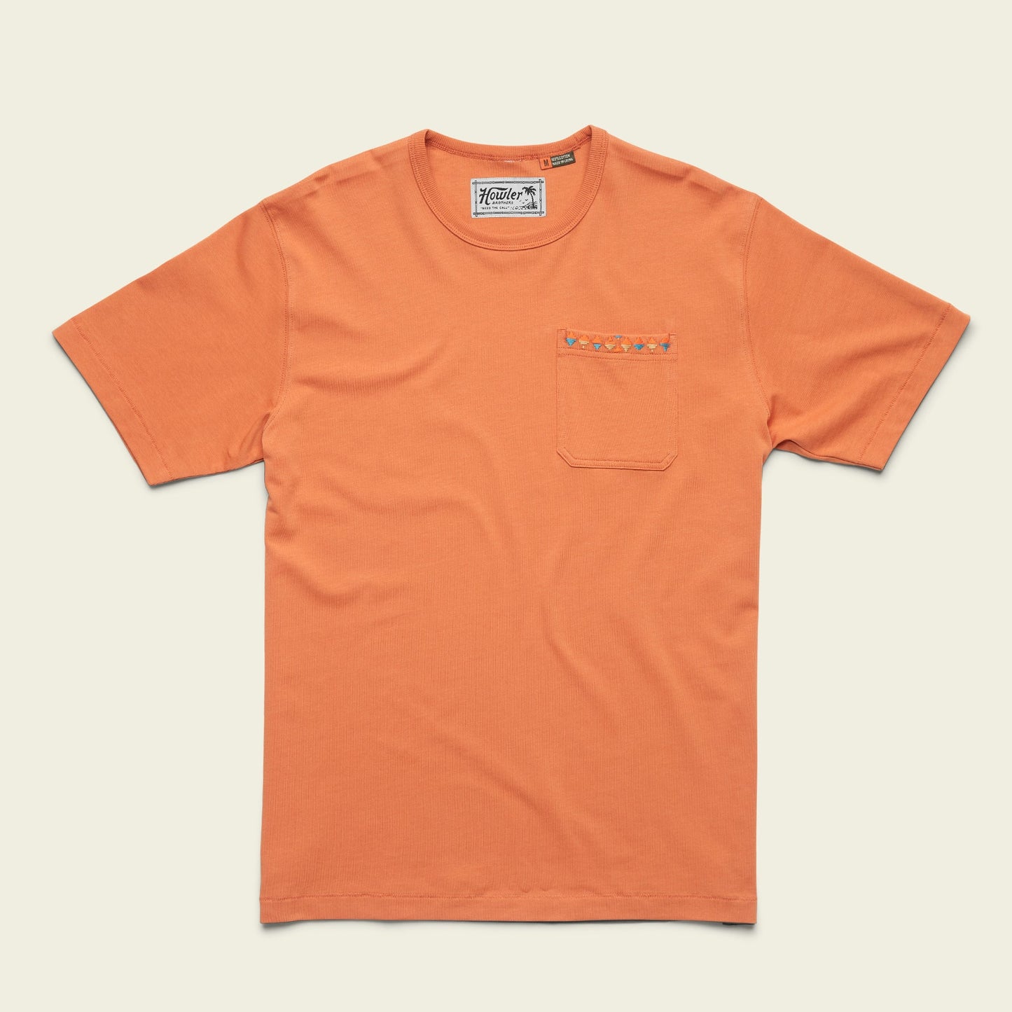 An orange heavyweight cotton pocket t-shirt with a chest pocket featuring a small embroidered pattern along the top edge. The shirt is laid flat on a light background, channeling an 80s 90s inspired vibe. - View 1