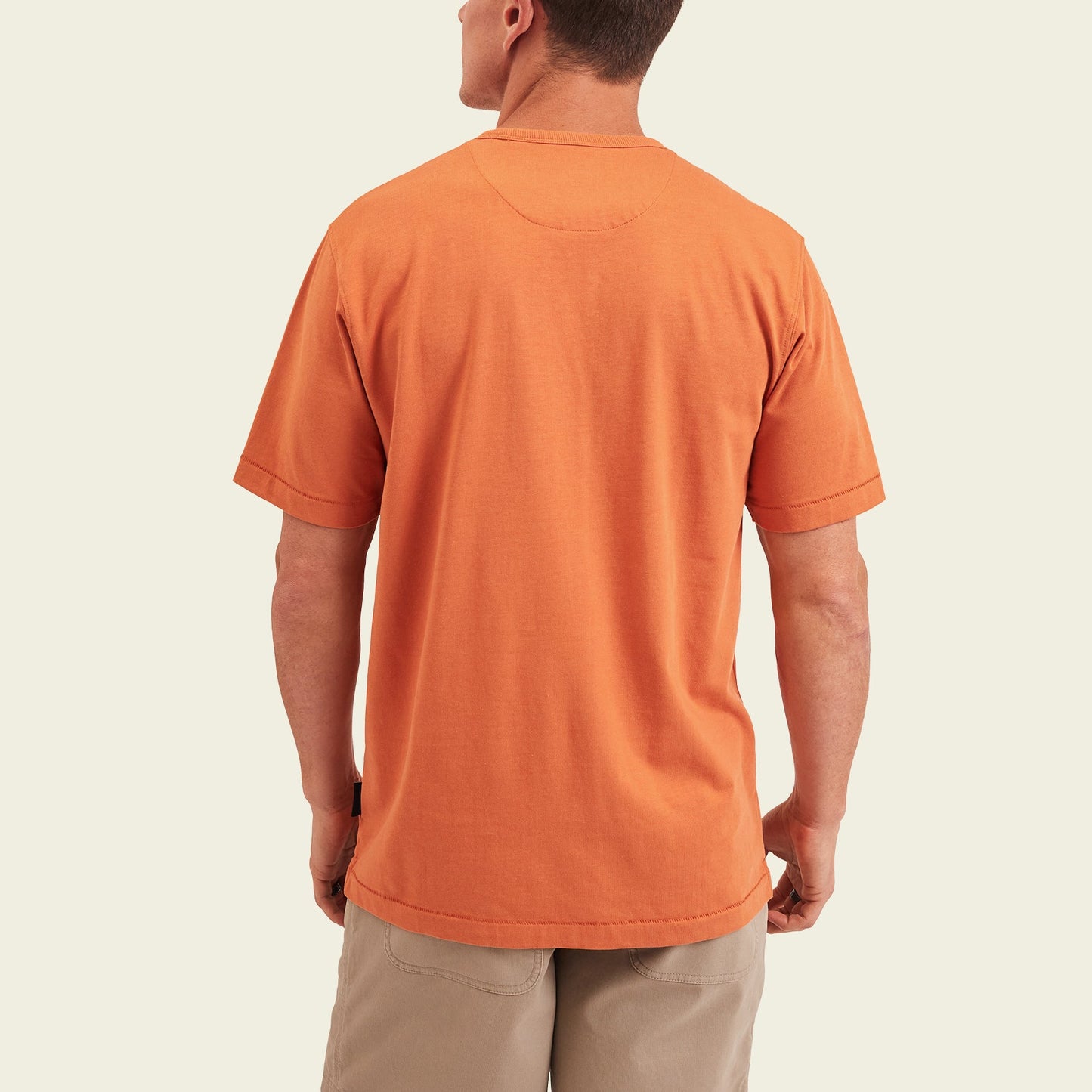 A man wearing a short-sleeve, 80s 90s inspired heavyweight cotton t-shirt in orange and light beige shorts is standing with his back to the camera against a plain light background. - View 5