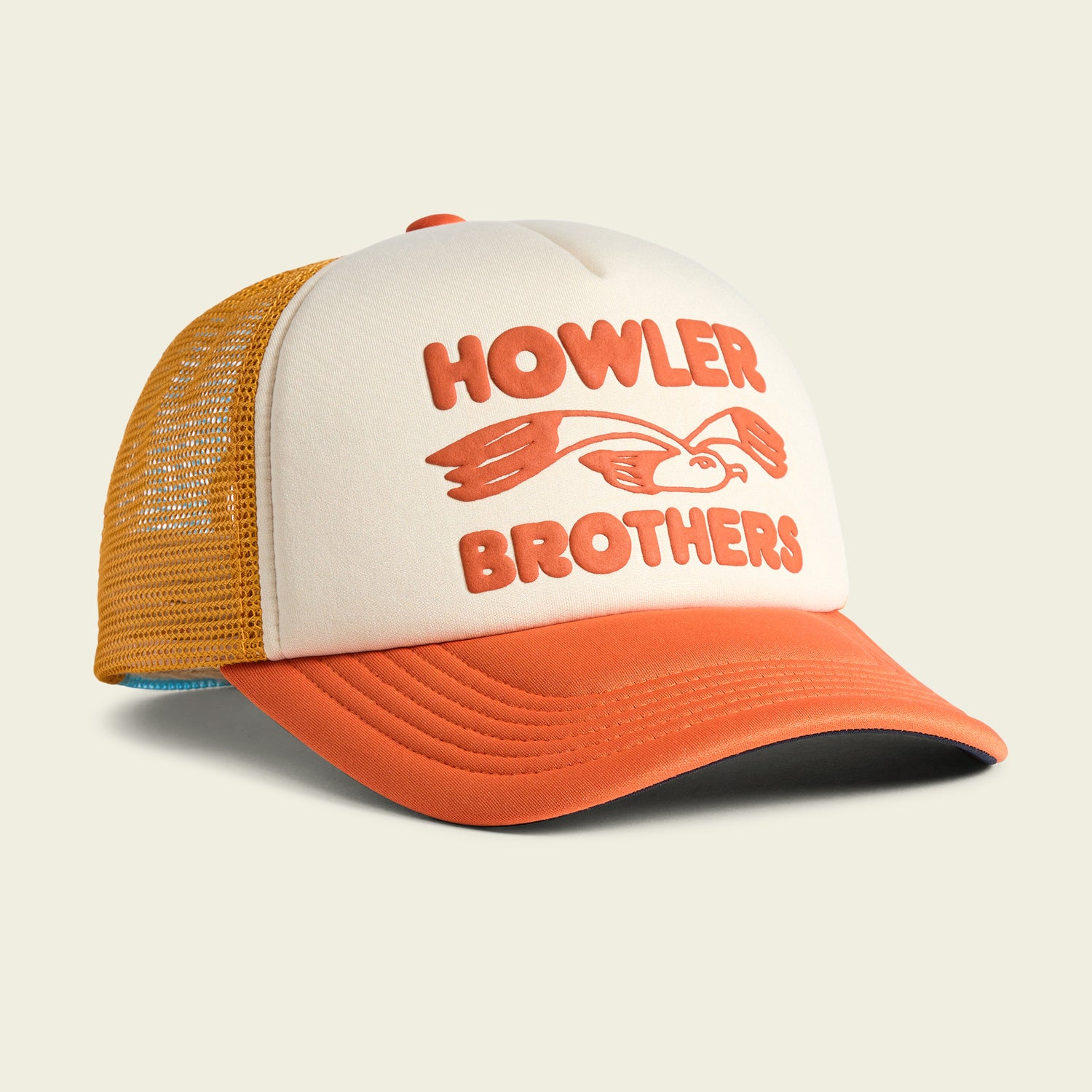 A cream and orange vintage-inspired hat with a yellow mesh back, featuring HOWLER BROTHERS and an illustrated bird with outstretched wings on the foam front panel.