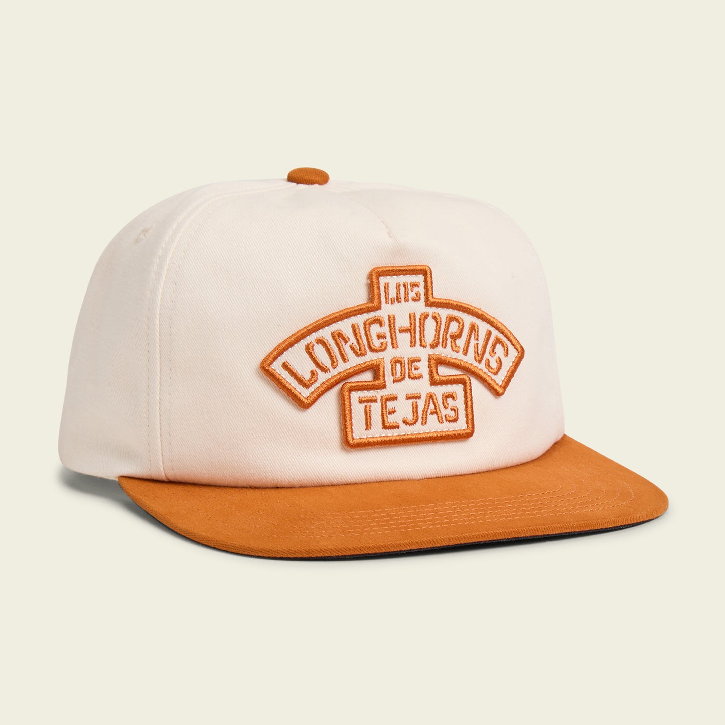 This unstructured snapback baseball cap features a white crown with a burnt orange brim and button. The front showcases Los Longhorns de Tejas in orange embroidery, honoring the University of Texas Longhorns and the year 1915. - View 1