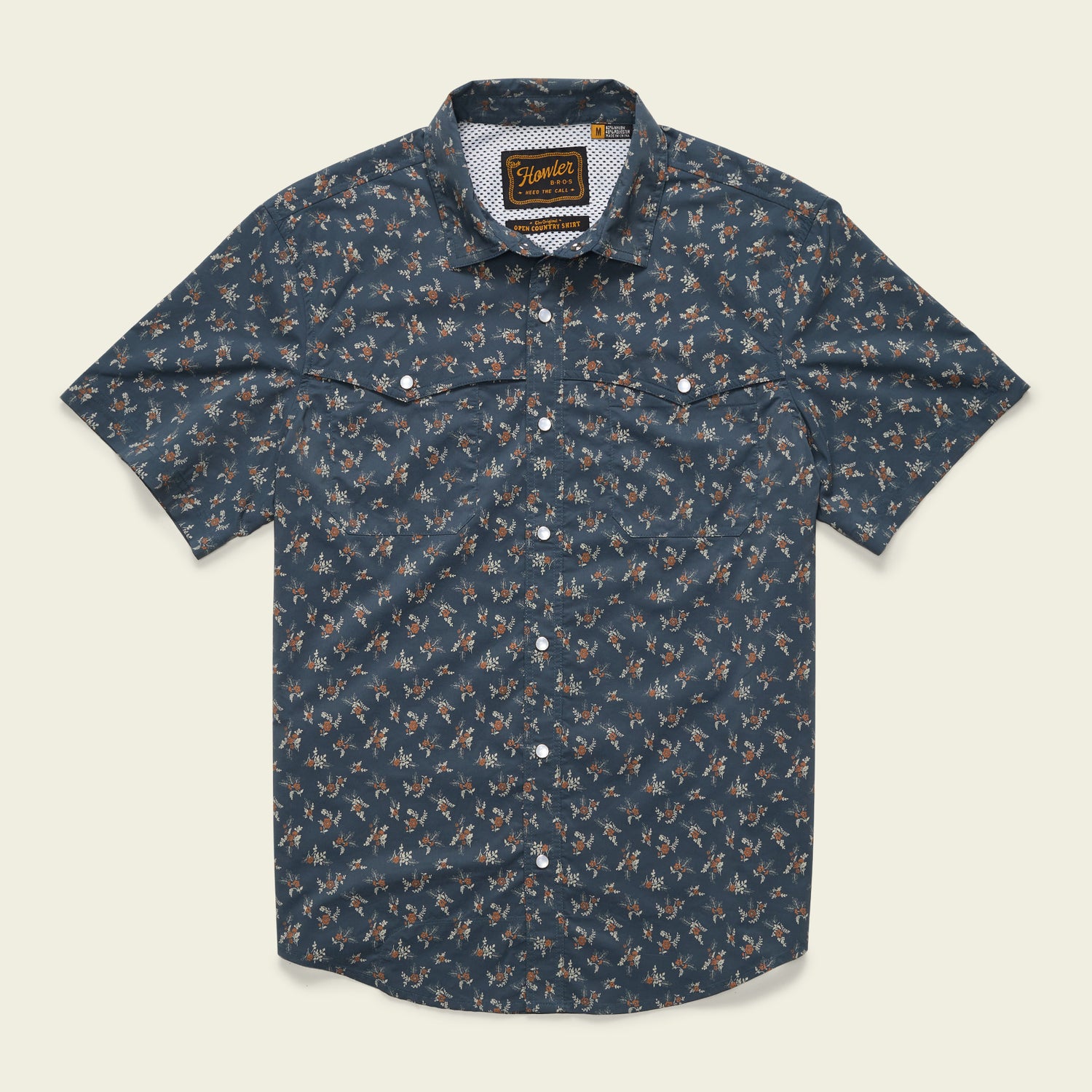 Short-sleeved, button-up technical utility shirt with a dark blue background and a small, all-over floral print. Features two chest pockets with button flaps, a patterned inner collar, and a vented rear yoke for added comfort.