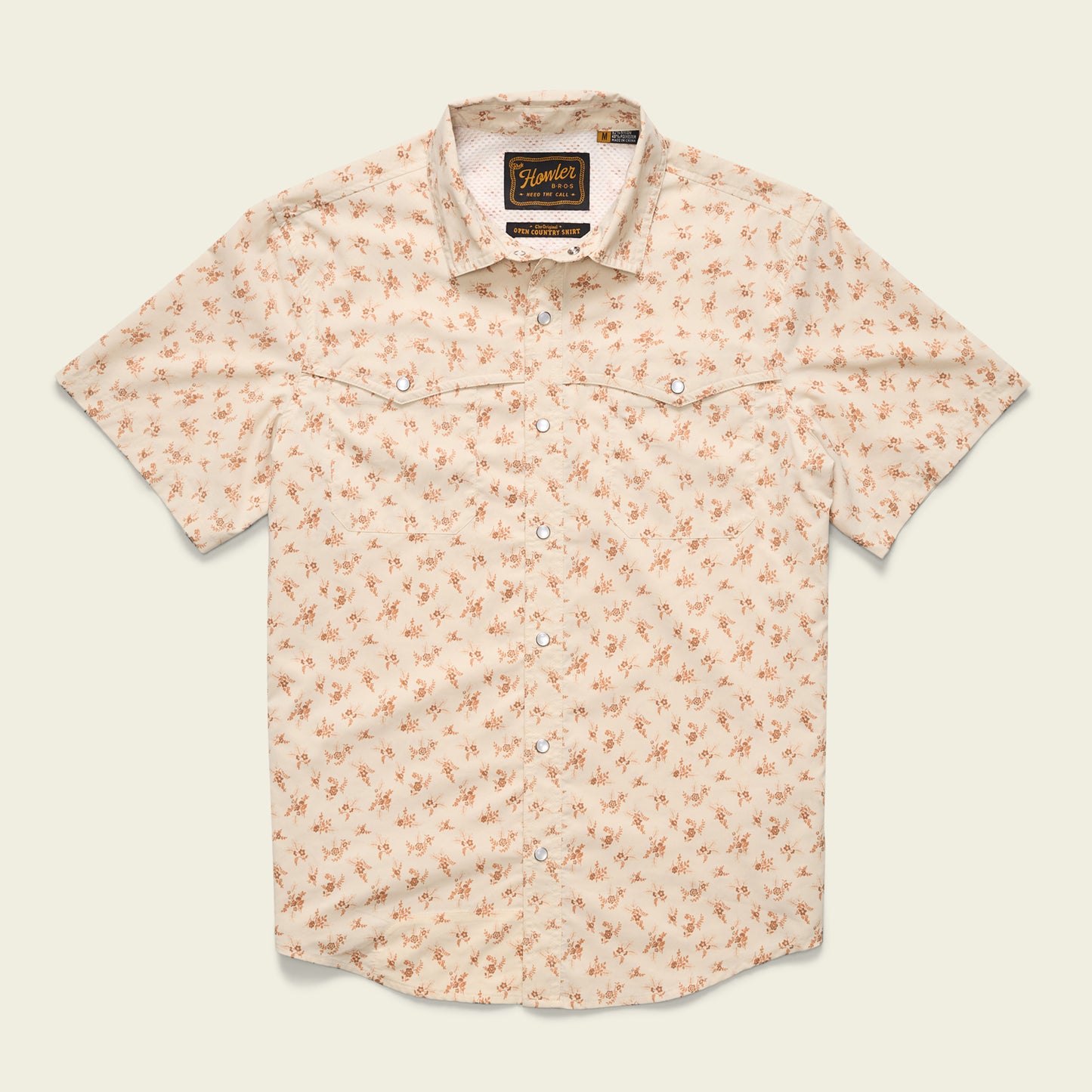 A short-sleeved, light beige button-up shirt with a small orange floral pattern, two chest pockets, pearl snaps, and a collar, crafted from nylon-poly fabric and laid flat against a plain background. - View 6