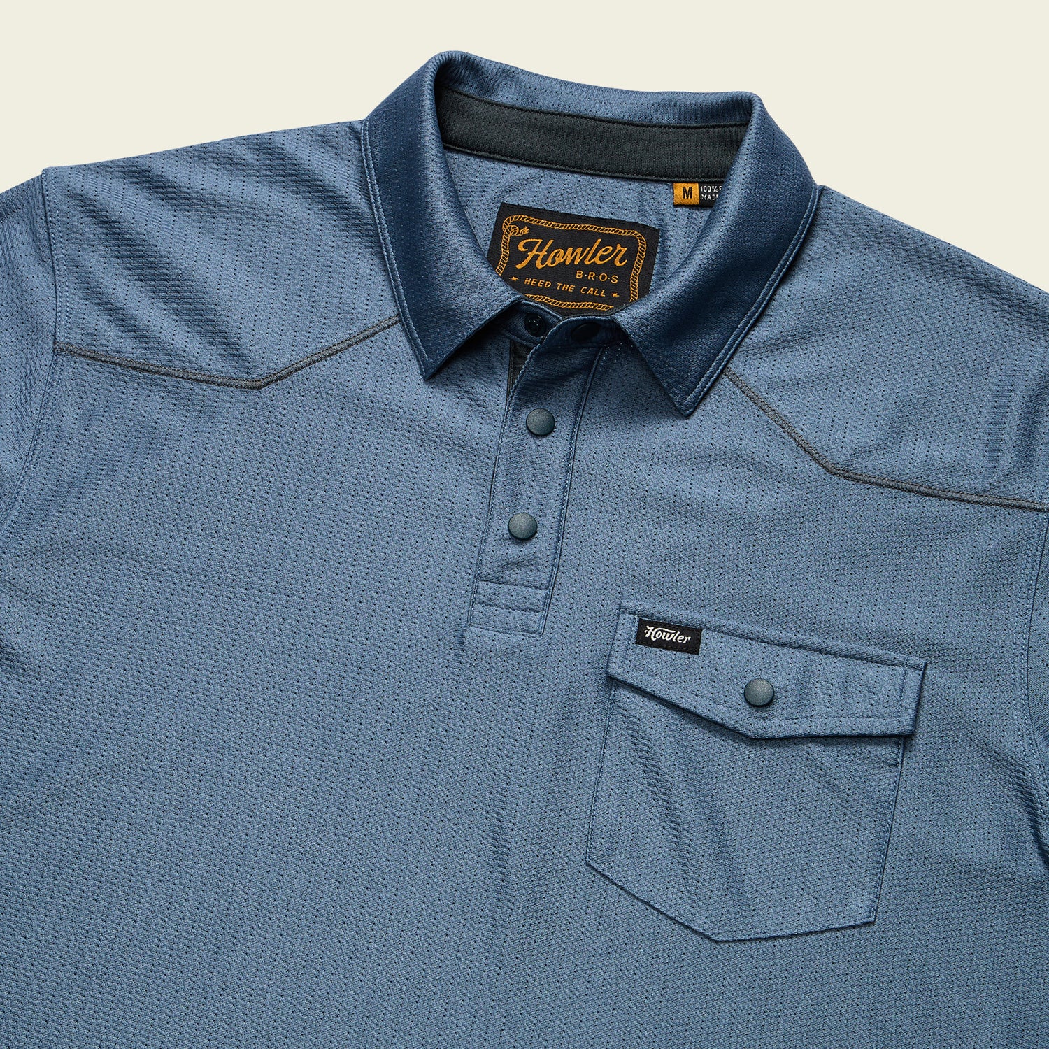A blue short-sleeve Tech Polo with three buttons, a front chest pocket with flap and button, made from breathable recycled polyester. Features the Howler Bros label on the pocket and inner collar tag. - View 3