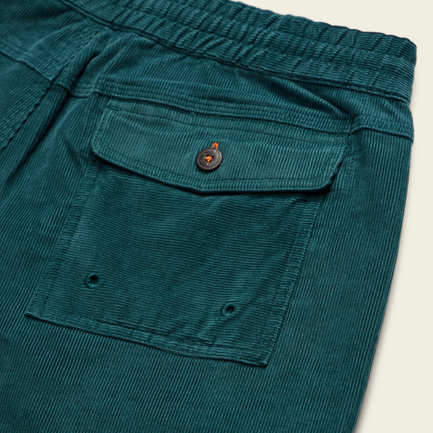 Close-up of a teal stretch cotton corduroy pocket with a flap, button closure, and elastic waistband—features seen on the Pressure Drop Cord Shorts—plus two small eyelets at the bottom for these comfortable shorts. - View 6