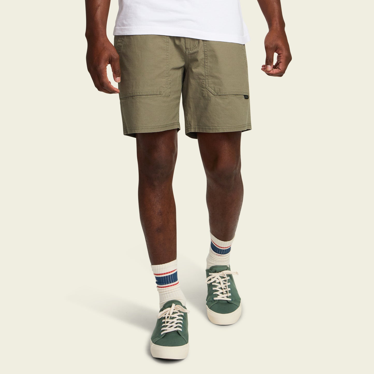 A person wearing Quonset Camp Shorts made from ripstop cotton, a white t-shirt, white socks with blue and red stripes, and green sneakers stands against a plain light background. - View 3