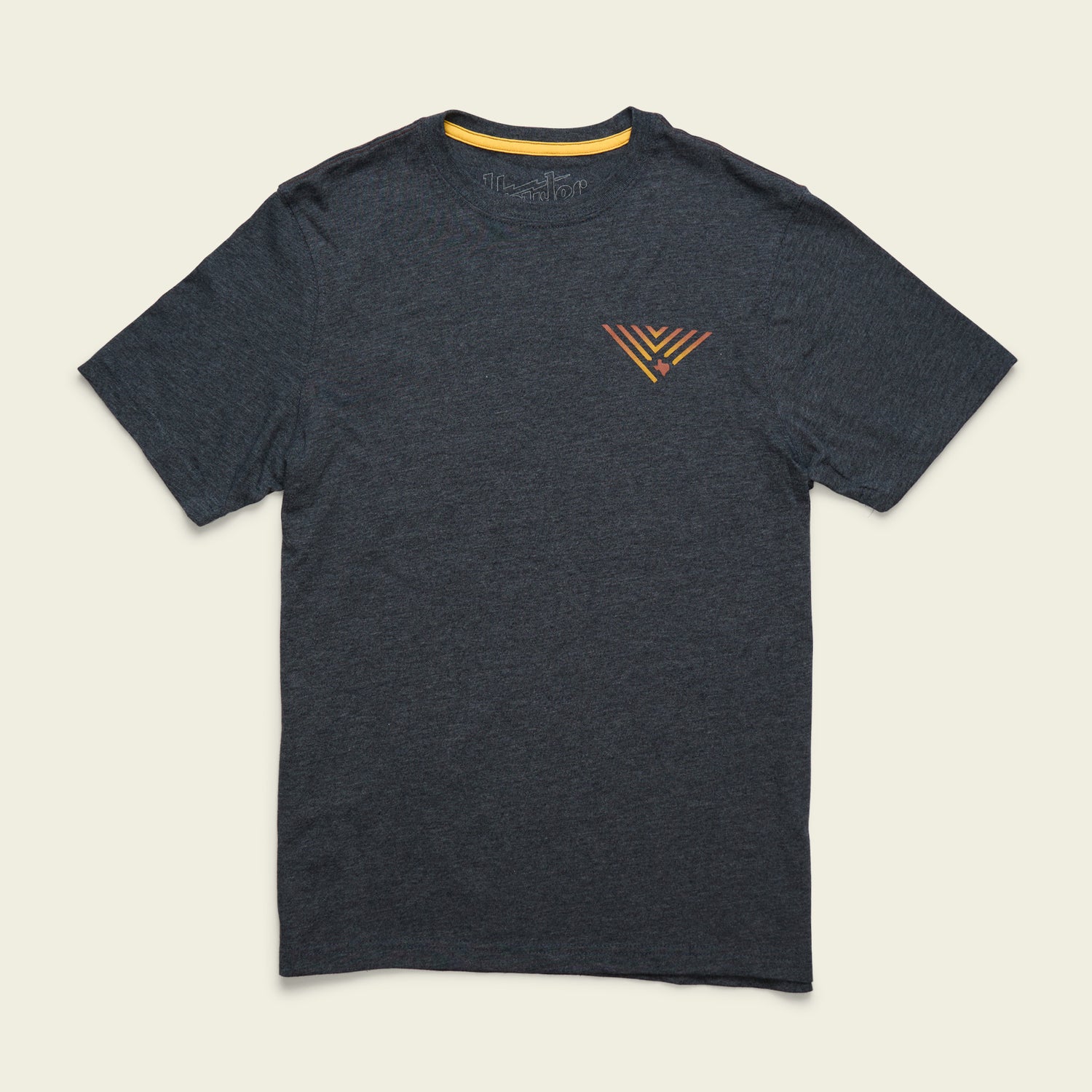 A dark gray short-sleeve t-shirt from the JT Van Zandt Collection, featuring a small, colorful geometric triangle design on the left chest, is displayed on a light, neutral background. Part of our Howler Select T-Shirts series. - View 3