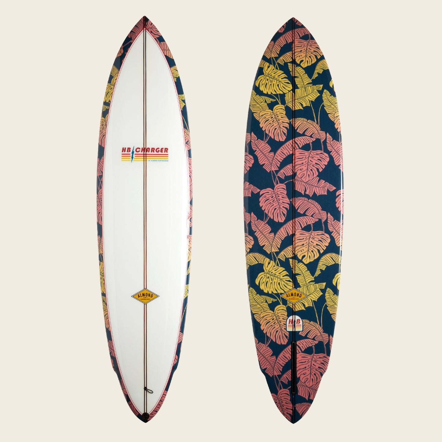 Two surfboards side by side: the left is mostly white with patterned edges and an HB Charger surfboard logo, while the right showcases a bold tropical leaf print in pink and yellow on a dark background. - View 1